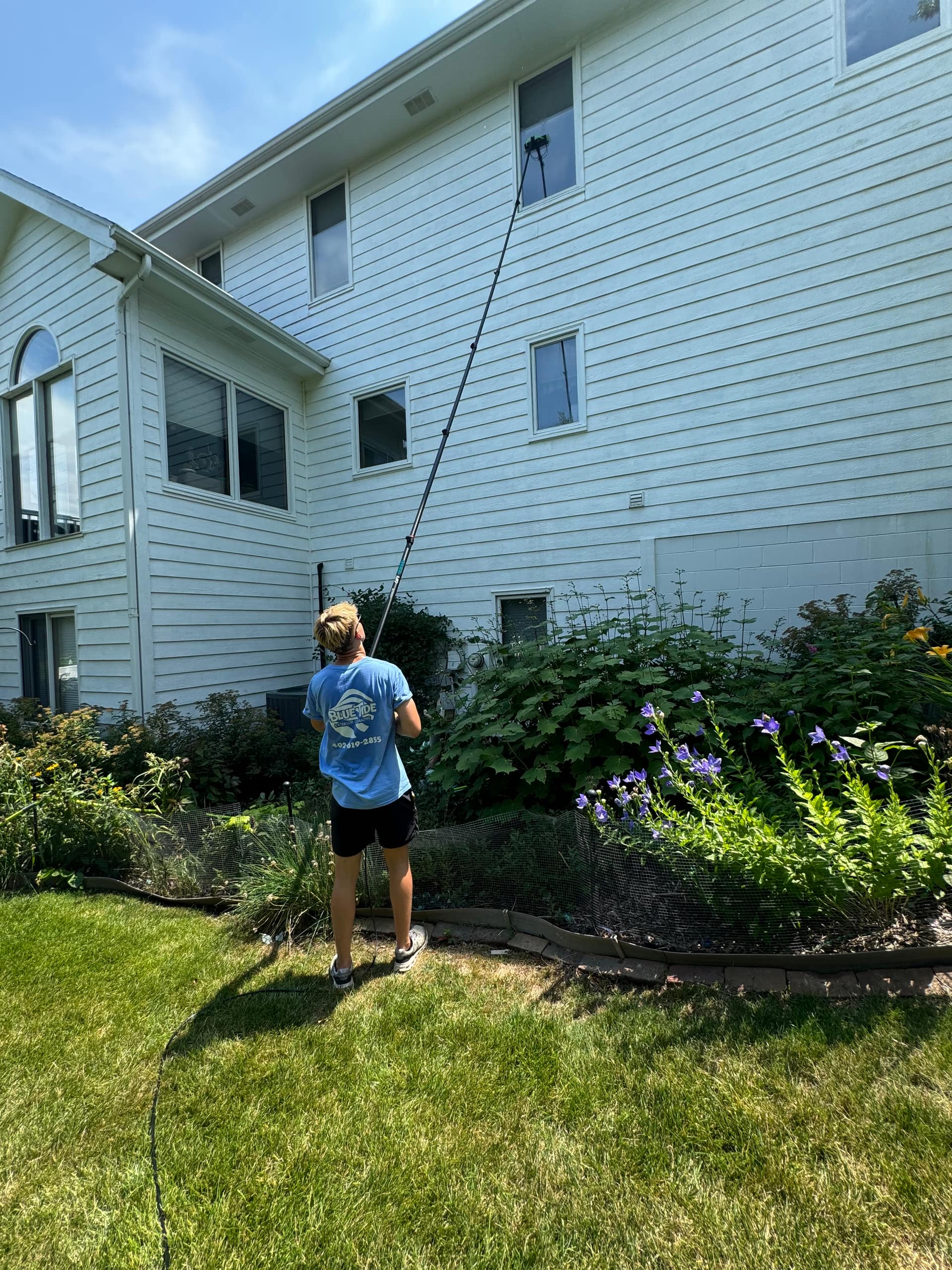 Bluetide crew member water-fed-pole-cleaning the second story of an Omaha home